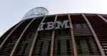 Fachada moderna de um edifício com o logótipo da IBM em destaque, com estrutura em madeira e vidro e uma torre envidraçada ao fundo."